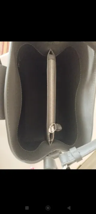 Bolso gris con cierre metálico.