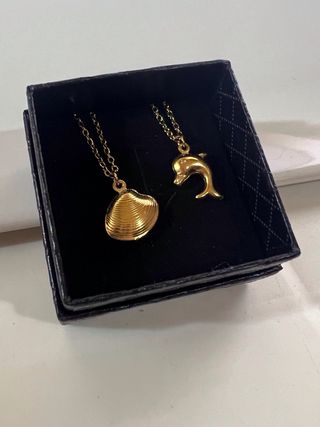 Colgante de dorado con forma de concha y delfín.