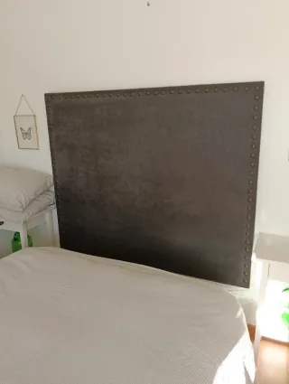 Cabecero tapizado gris con tachuelas doradas
