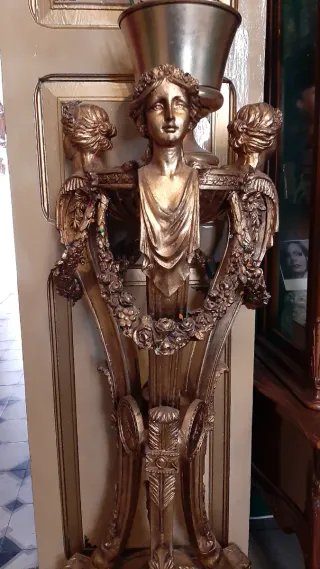 Pedestal antiguo dorado con figuras en pan de oro.