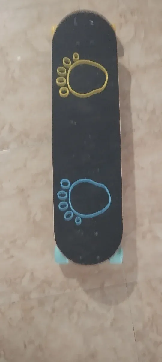 Monopatín negro con huellas amarillas y azules