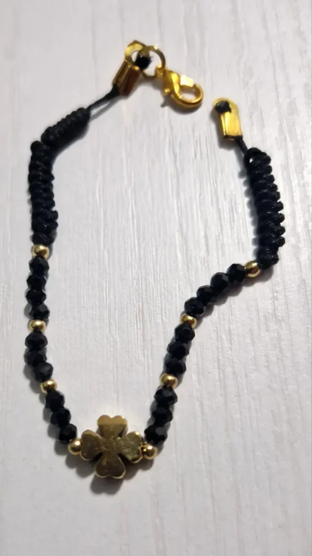 Pulsera negra con trébol dorado