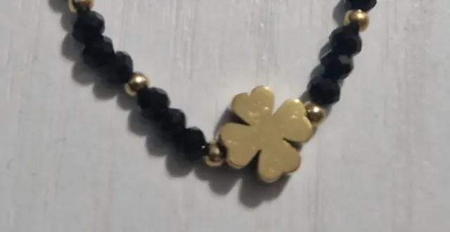 Pulsera negra con trébol dorado
