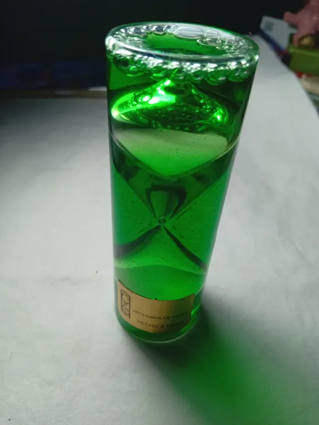 Reloj de arenadentro de botella de líquido verde