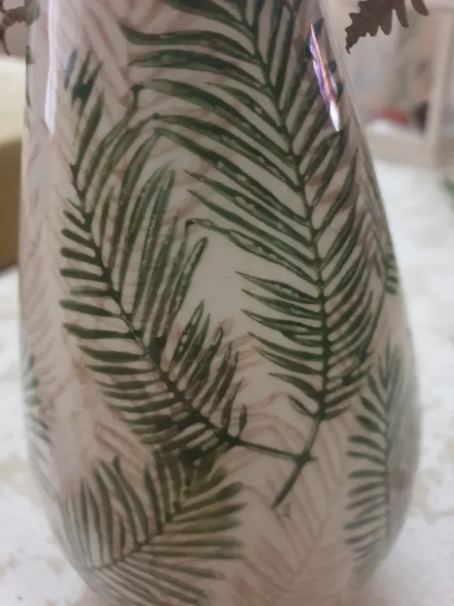 Jarrón de cerámica con hojas verdes