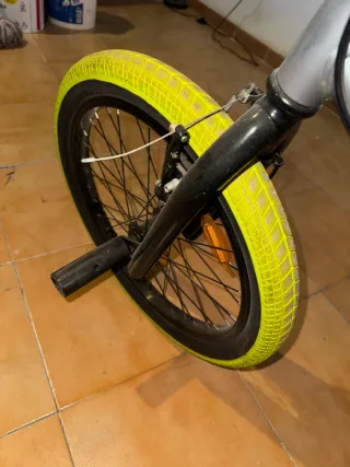 Bicicleta estilo BMX plateada con ruedas verdes