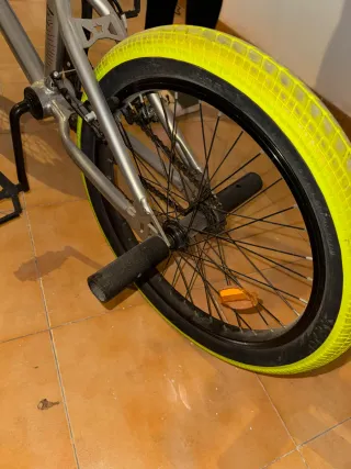 Bicicleta estilo BMX plateada con ruedas verdes