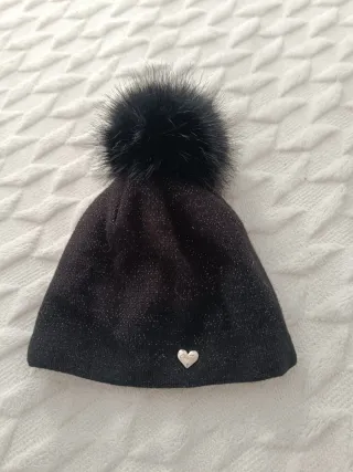 Gorro negro con pompón Lleva hilos plateados