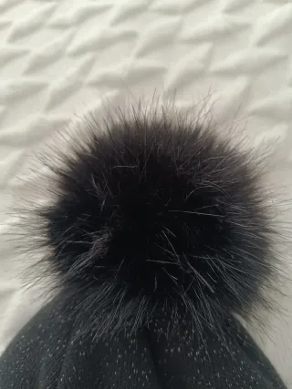 Gorro negro con pompón Lleva hilos plateados