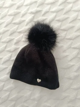 Gorro negro con pompón Lleva hilos plateados