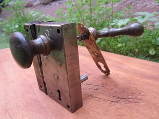 Cerradura antigua con pomo y maneta verdes.