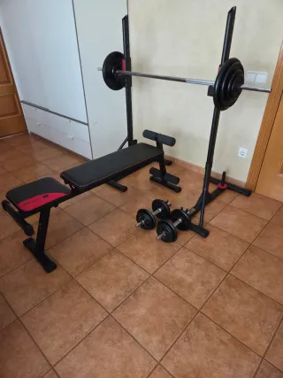 Rack y banco de gimnasio con pesas y mancuernas