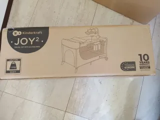 Cuna de viaje gris con cambiador y móvil