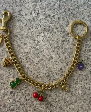 Colgante bolso Coach dorado con charms
