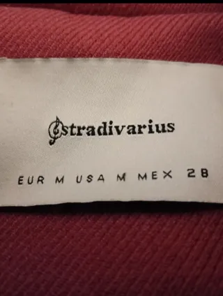 Abrigo Stradivarius rosa y plumas naranja.