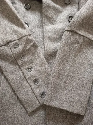 Abrigo gris elegante hombro abullonado.