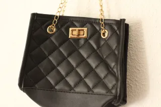 Bolso negro con detalles dorados.