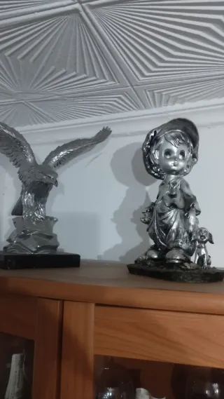 Lote 2 figuras plateadas: águila y niño