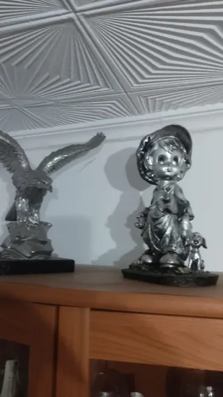 Lote 2 figuras plateadas: águila y niño