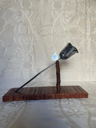 Escultura de rosa de metal, con base de madera.