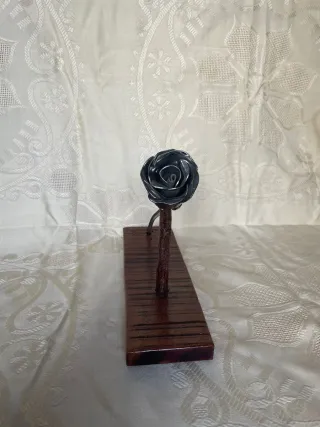 Escultura de rosa de metal, con base de madera.