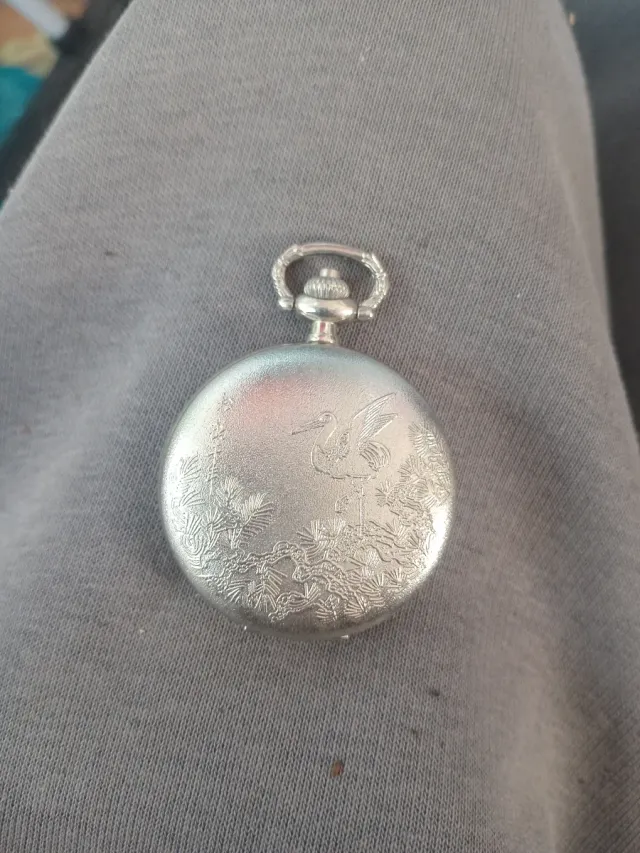 Reloj de bolsillo plateado con grulla