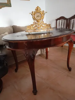 Mesa de madera ovalada con reloj antiguo