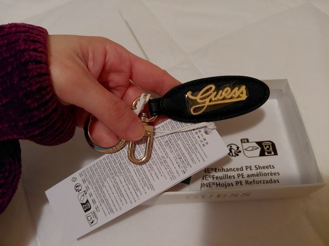 Portachiavi Guess nero con logo dorato.