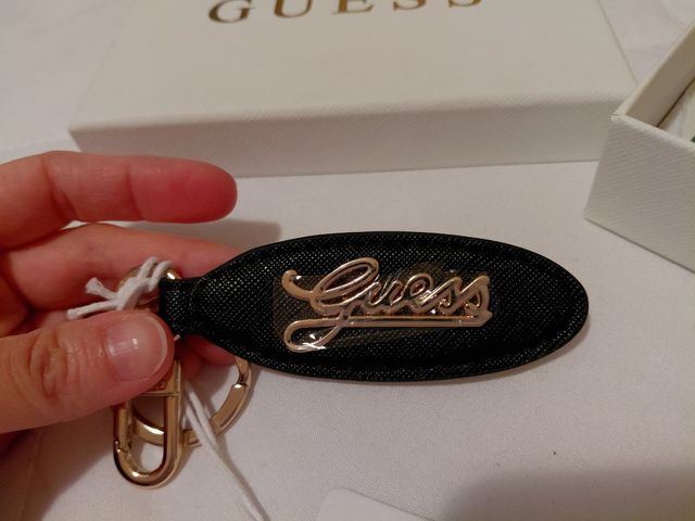 Portachiavi Guess nero con logo dorato.
