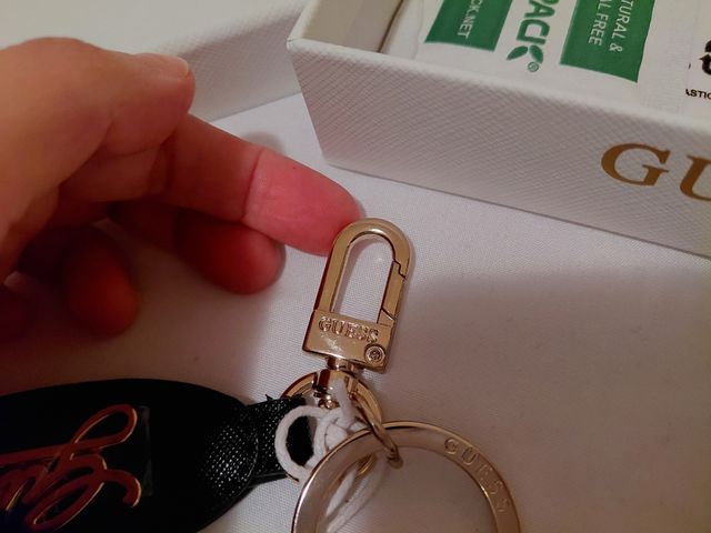 Portachiavi Guess nero con logo dorato.