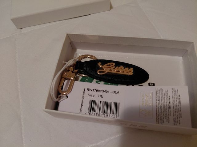 Portachiavi Guess nero con logo dorato.