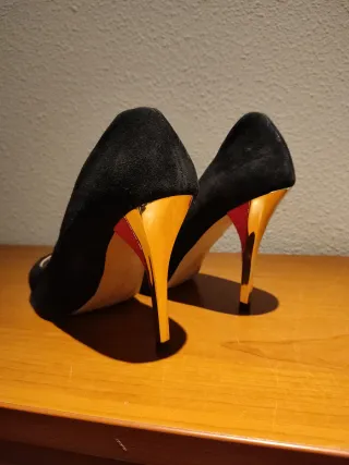 Zapatos de tacón negros y dorados con detalle rojo