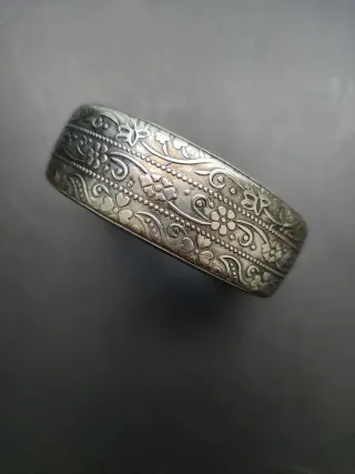 Brazalete plateado con detalles relieve florales.