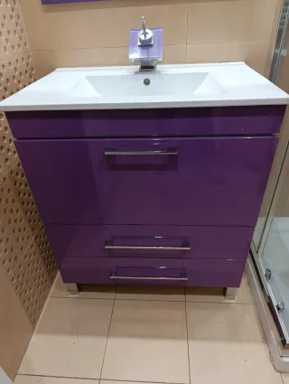 Mueble de baño morado con lavabo, espejo y grifo.