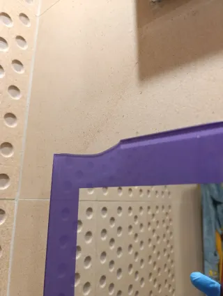 Mueble de baño morado con lavabo, espejo y grifo.
