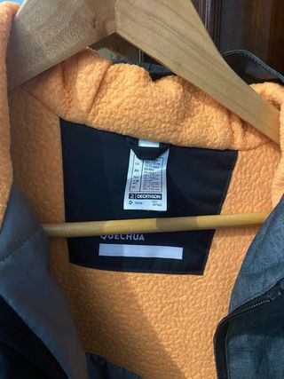 Chaqueta Quechua impermeable con forro naranja.
