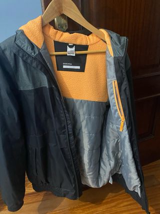 Chaqueta Quechua impermeable con forro naranja.