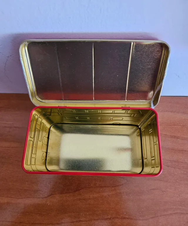 Hola    Caja metálica dorada con borde rojo