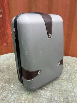 Maleta de viaje plateada con algún roto