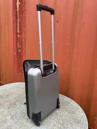 Maleta de viaje plateada con algún roto