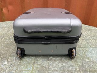 Maleta de viaje plateada con algún roto