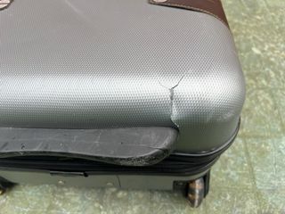 Maleta de viaje plateada con algún roto