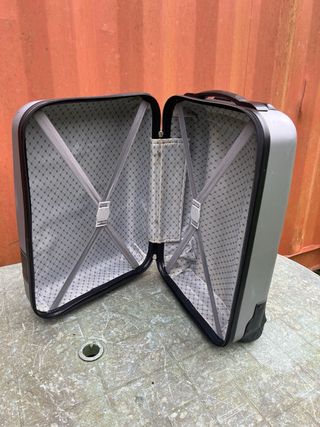Maleta de viaje plateada con algún roto