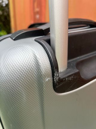 Maleta de viaje plateada con algún roto