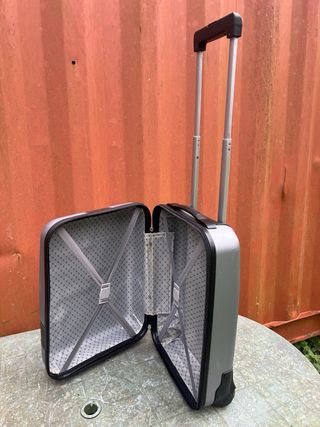 Maleta de viaje plateada con algún roto