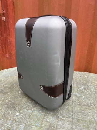 Maleta de viaje plateada con algún roto
