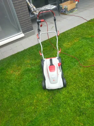 Cortacésped eléctrico blanco y rojo y herramienta