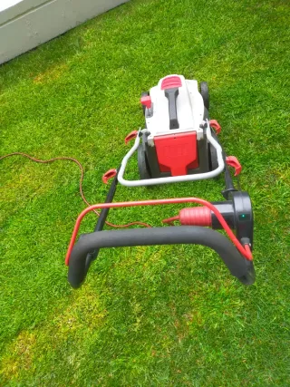 Cortacésped eléctrico blanco y rojo y herramienta