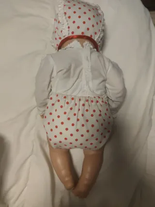 Muñeco bebé con traje blanco y lazo rojo