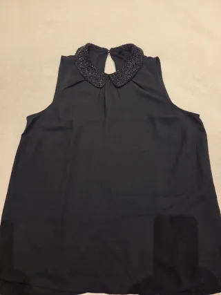 Blusa negra sin mangas con cuello adornado